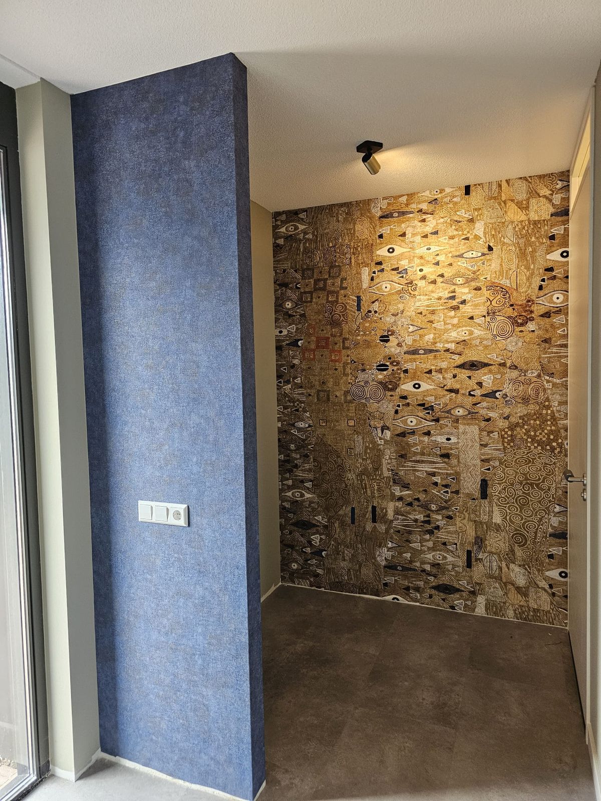 Portfolio: Goudkleurig grafisch behang naast blauwe muur