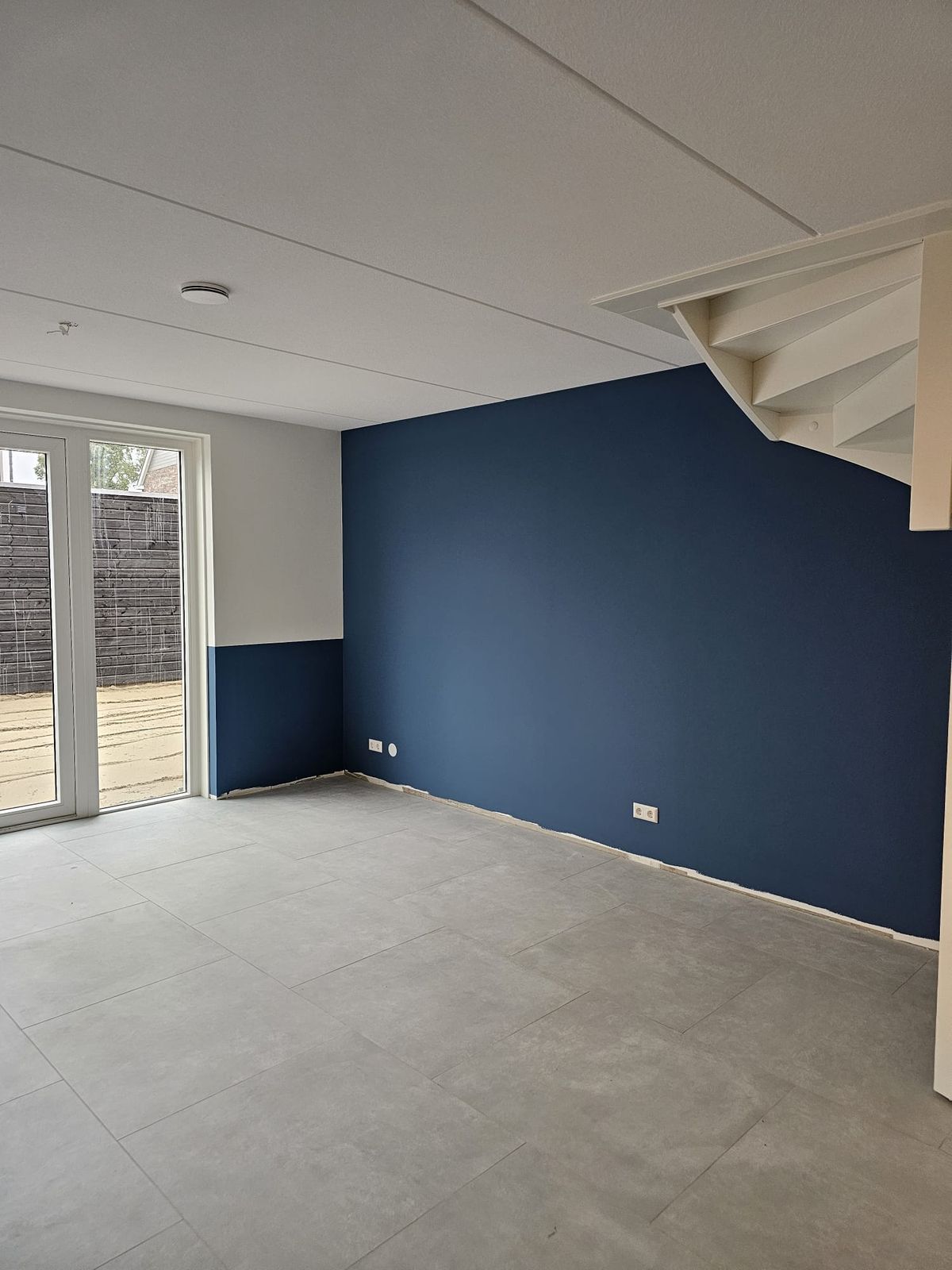 Portfolio: Marineblauwe accentwand in woonkamer met trap